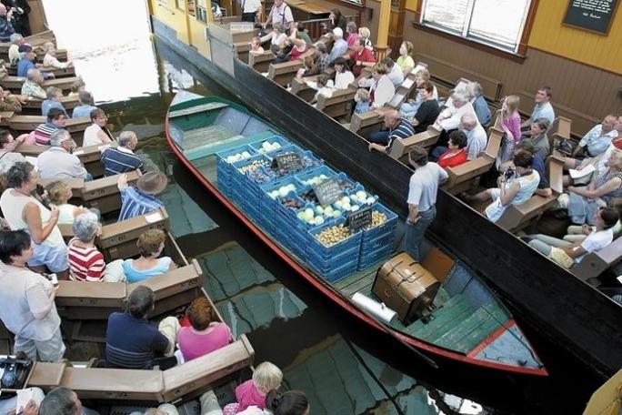 A man on a small boat with vegetables in boxes