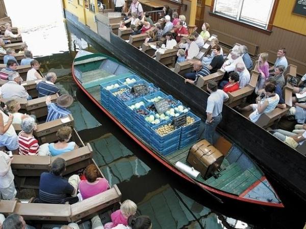 A man on a small boat with vegetables in boxes