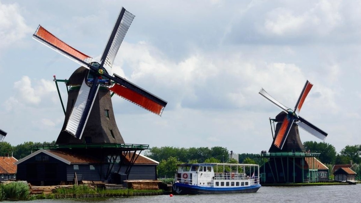 The boat on a river next to two big windmills