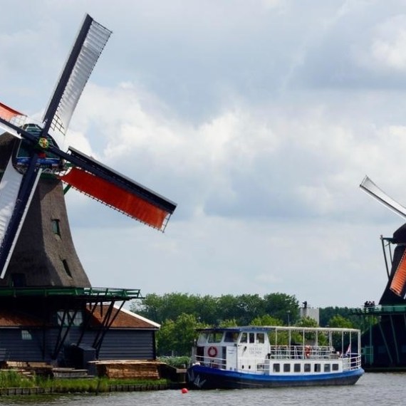 The boat on a river next to two big windmills