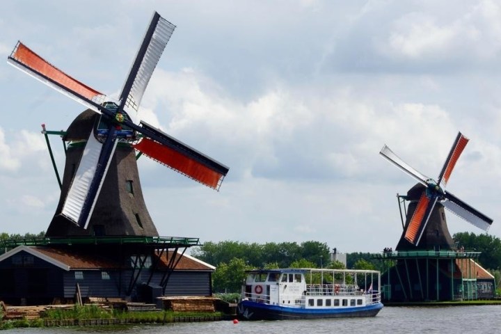 The boat on a river next to two big windmills