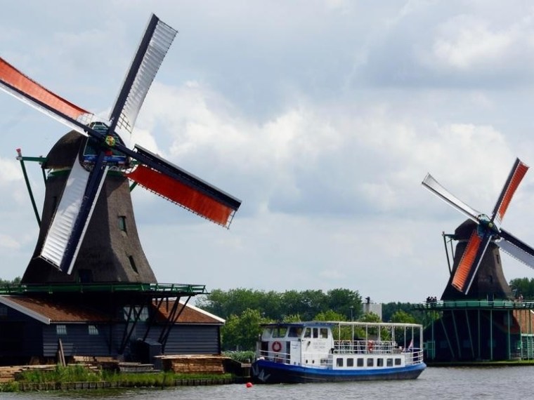The boat on a river next to two big windmills