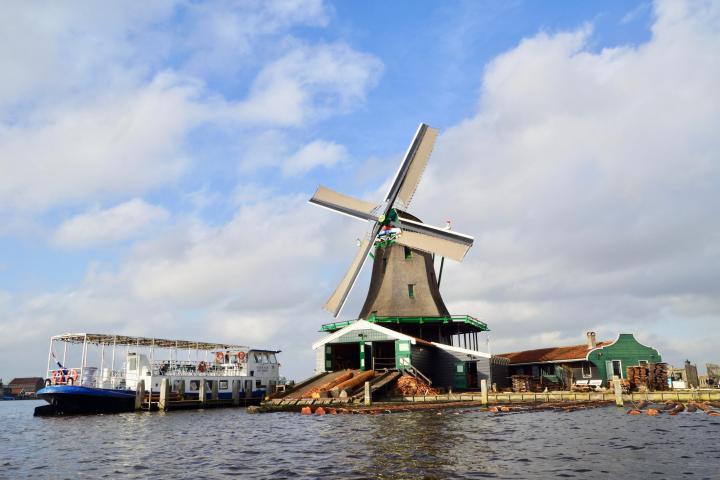 One windmill next to a river and a boat