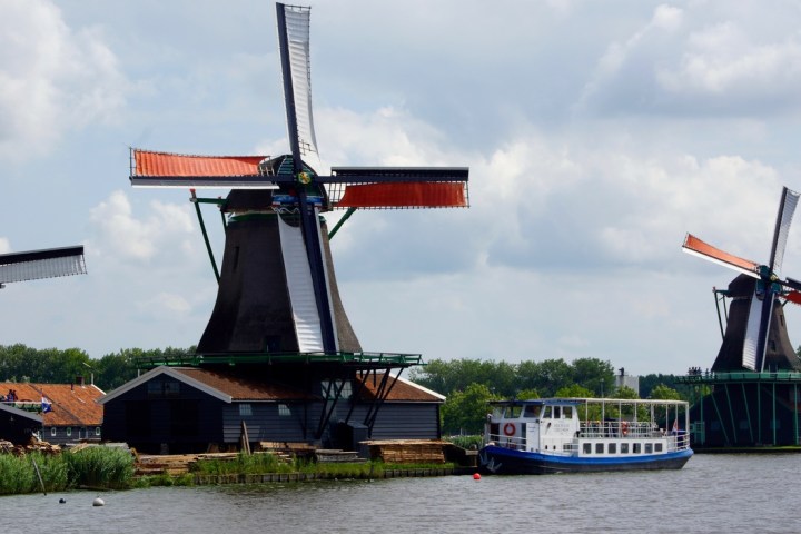 Two big windmills nect to a river and the boat next to them