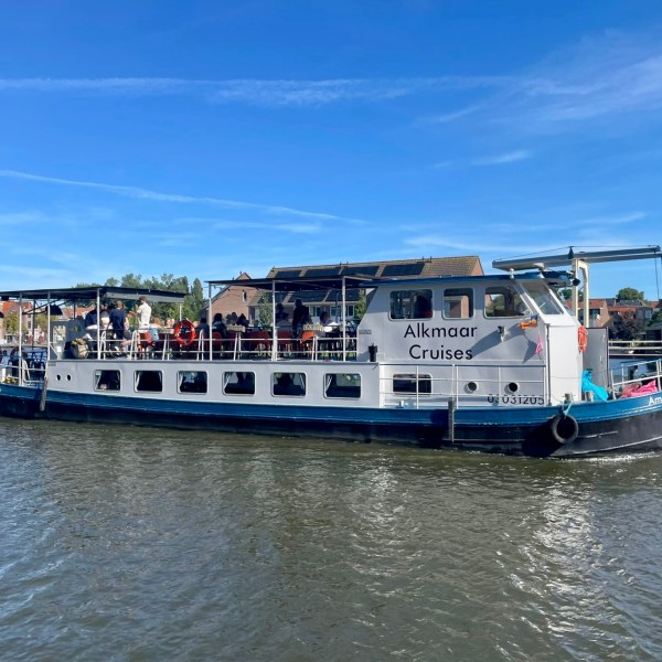Tour boat on a river with people onboard, clear blue sky in the background.