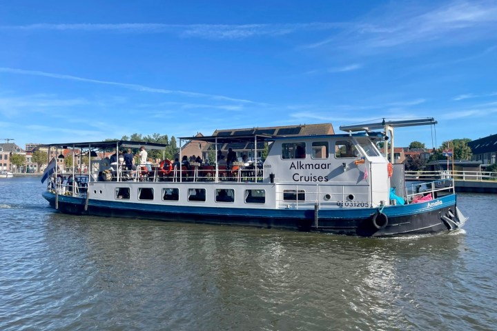 Tour boat on a river with people onboard, clear blue sky in the background.