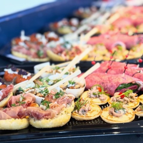 Assorted canapés on trays with meats, breads, and garnishes displayed elegantly.